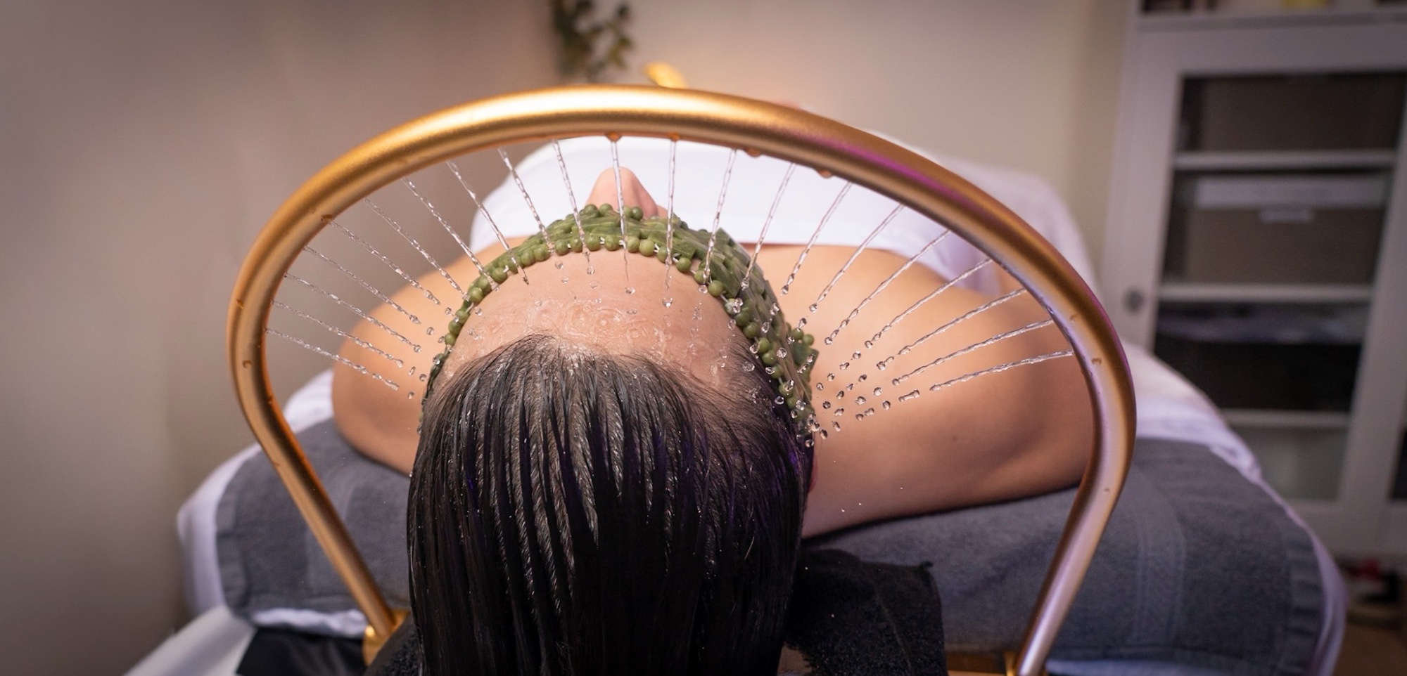 Woman under a head spa shower at Beauty and the Barber in Edmonds